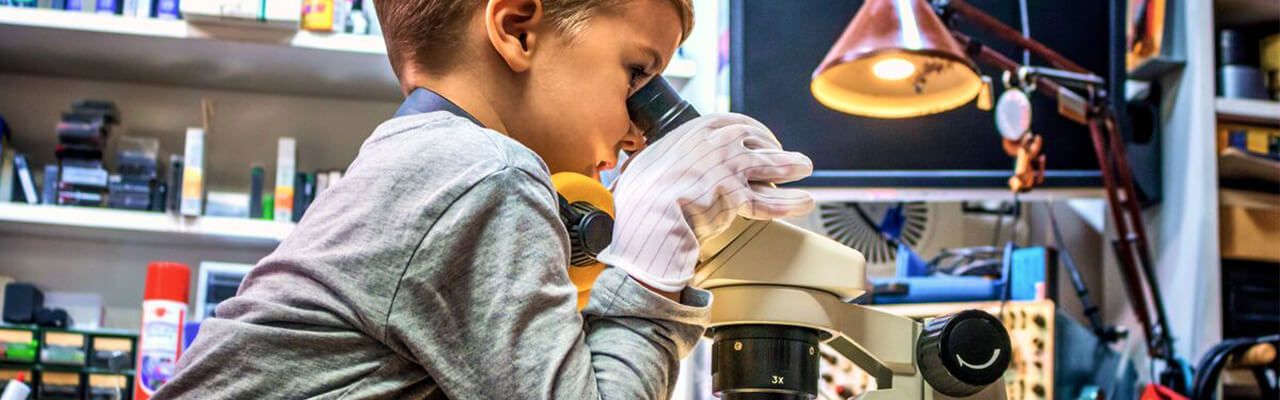 in copil se uita prin microscop