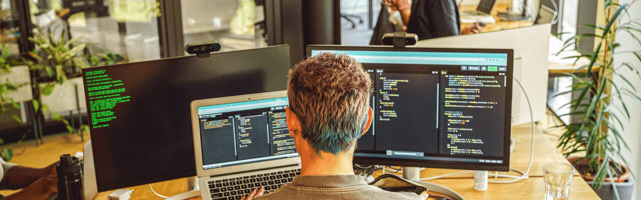 un programator in fata a 3 monitoare